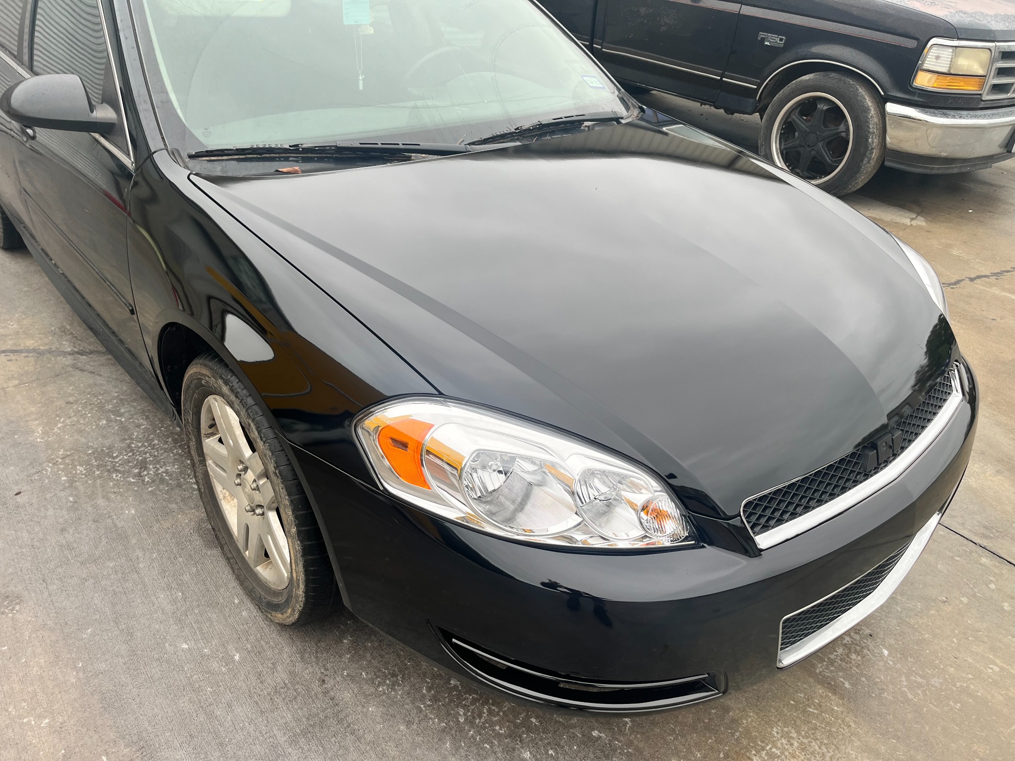 Black Chevrolet Impala after front paint refinishing, viewed from the passenger side.