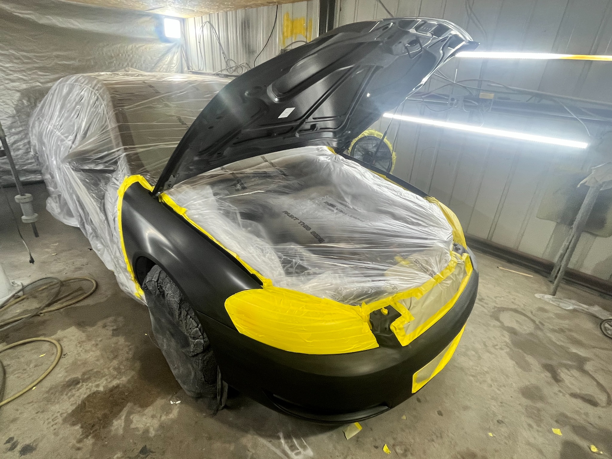 Black Chevrolet Impala masked for paint refinishing on the front body panels.