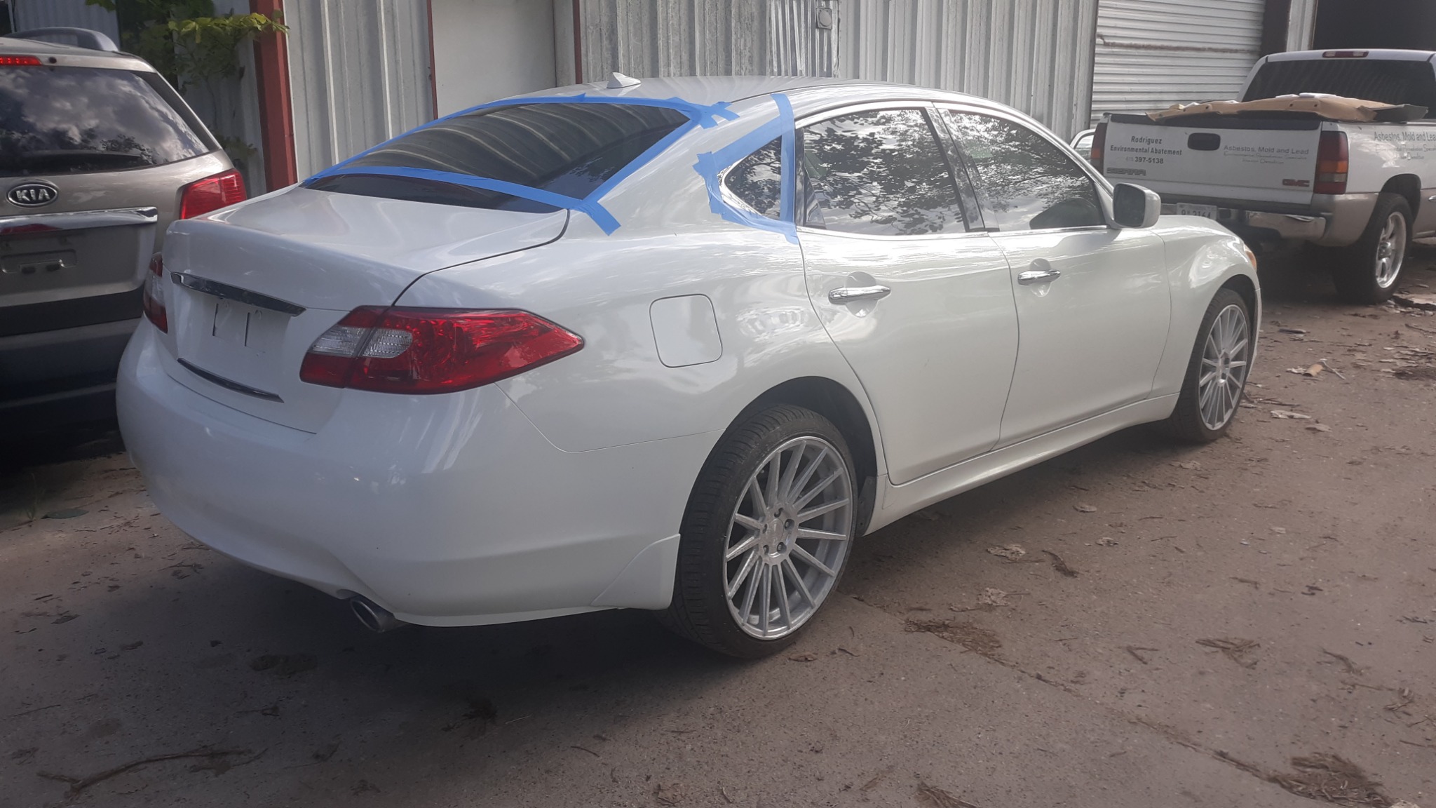 White Infiniti M37 after rear bodywork, with masking tape still visible around the rear glass.