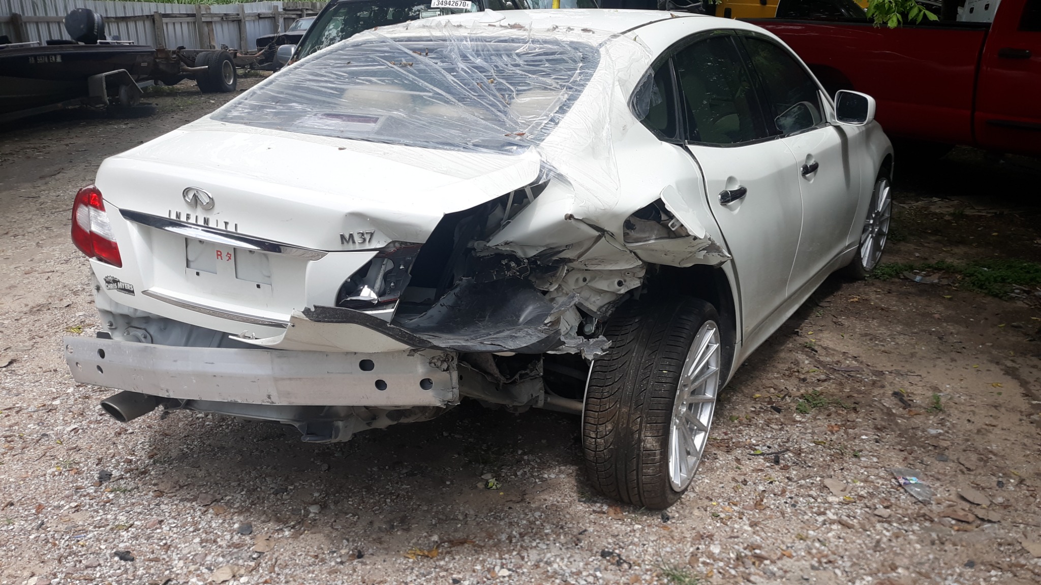 White Infiniti M37 before repair, with damage to the right rear quarter and bumper area.